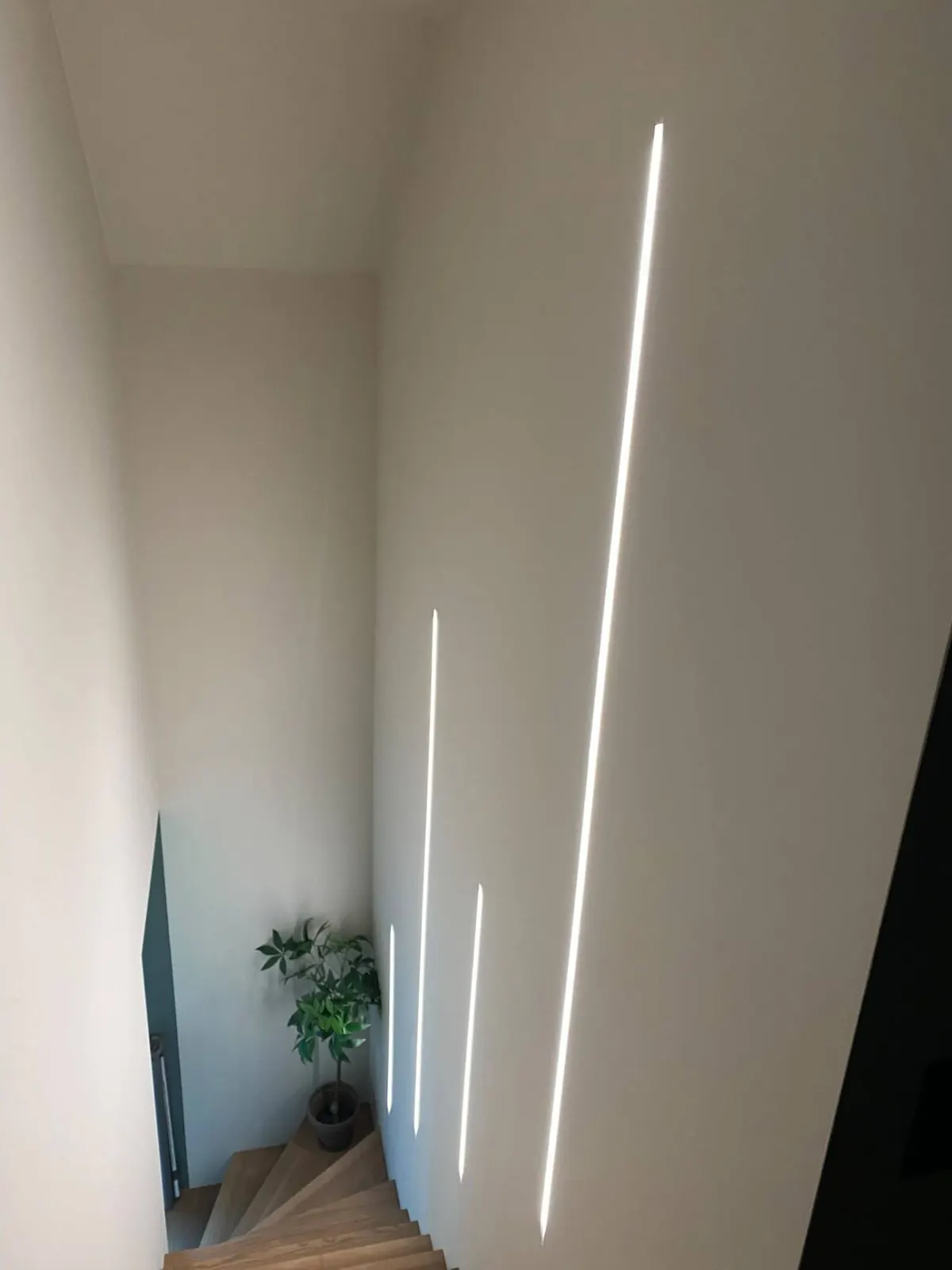 Éclairage architectural par lignes LED murales dans un escalier à Lobbes, vue en descente