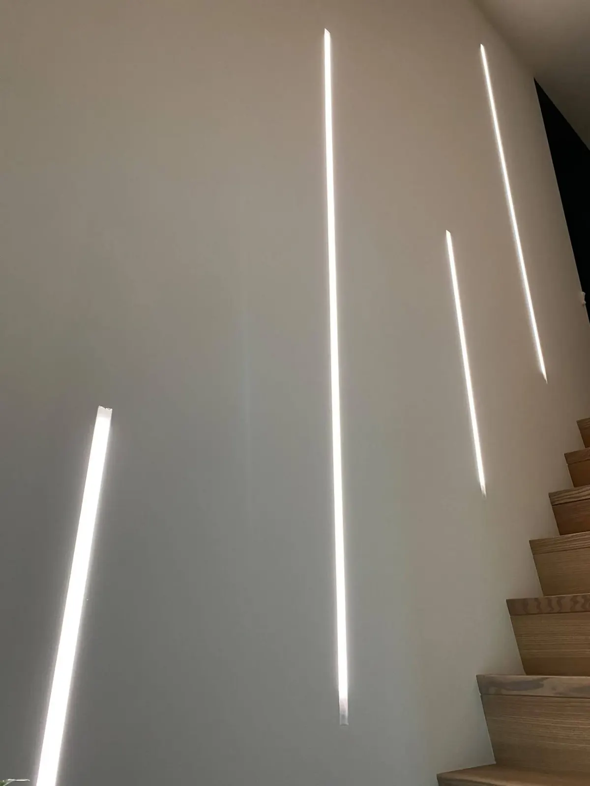 Lignes LED verticales intégrées dans le mur d'un escalier à Lobbes, détail de la finition