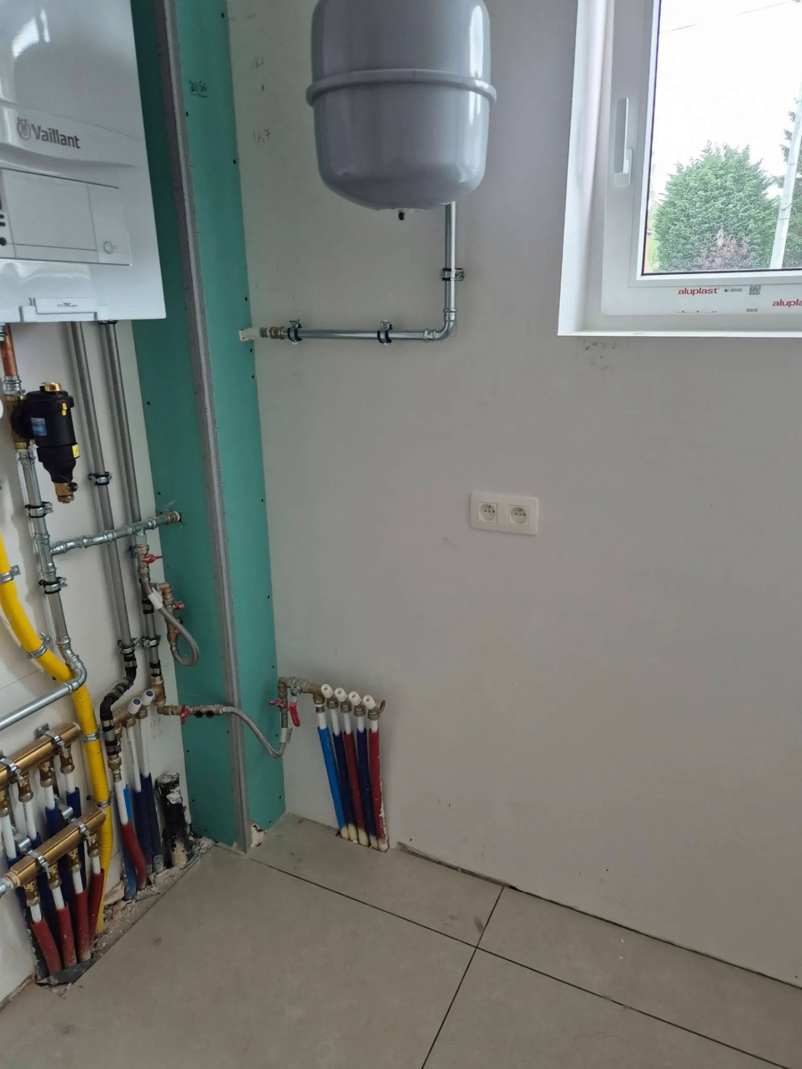 Local technique avec chaudière Vaillant, collecteurs PER et prises électriques à Soignies